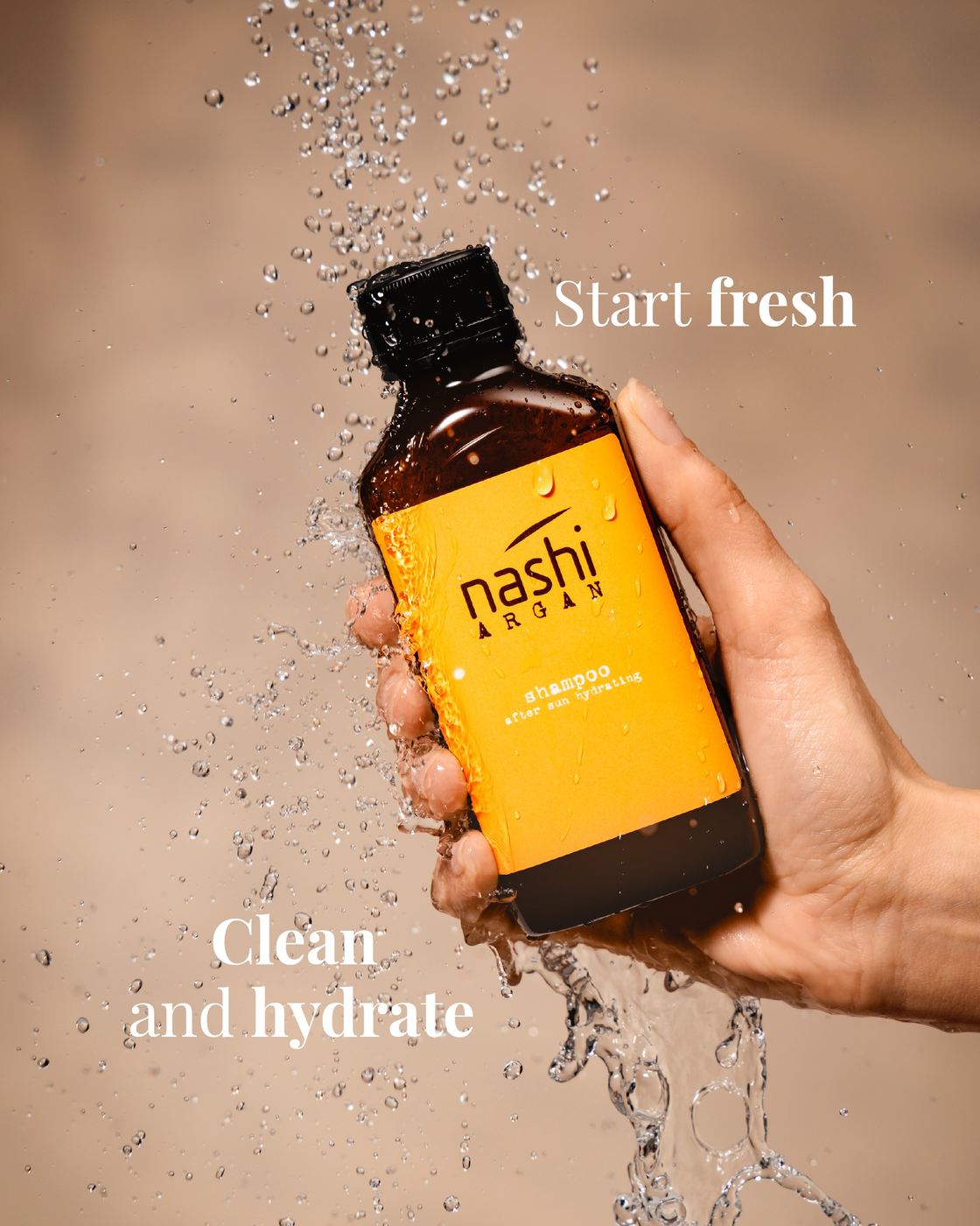 Un flacone Nashi Argan tra gli spruzzi d'acqua